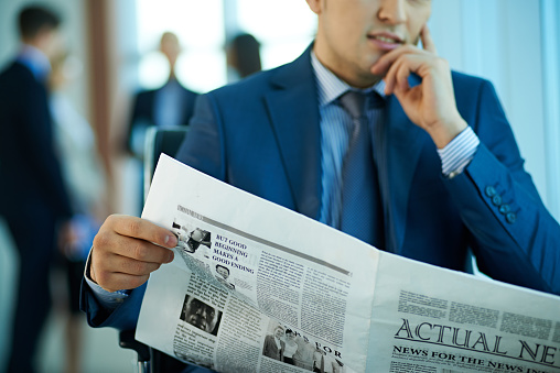One person reading newspaper. He working in business. He wants to find out actual news. Many people in background. It is perfect for using it in commercial and advertising photography, reports, books, presentation