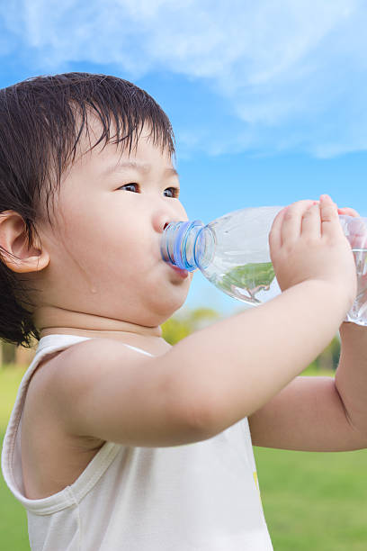 istock Little asian girl  drinking water from plastic bottle 542077950