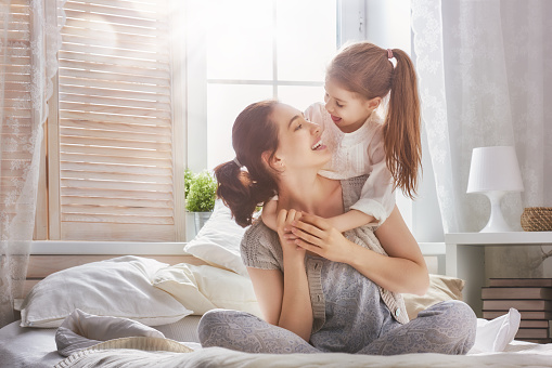 Happy loving family. Mother and her daughter child girl playing and hugging.