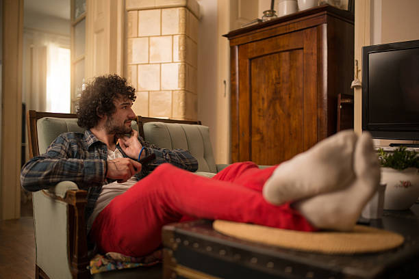 istock Relaxed man with feet up watching TV at home. 542081012