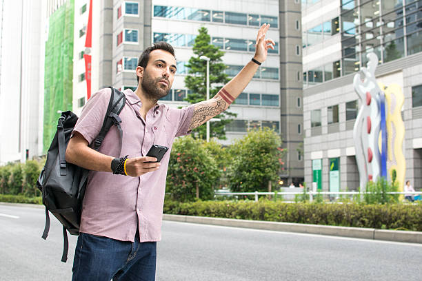 jovem branco homem uma segurar num cellphone neblina treinos taxi - fazendo sinal com a mão imagens e fotografias de stock