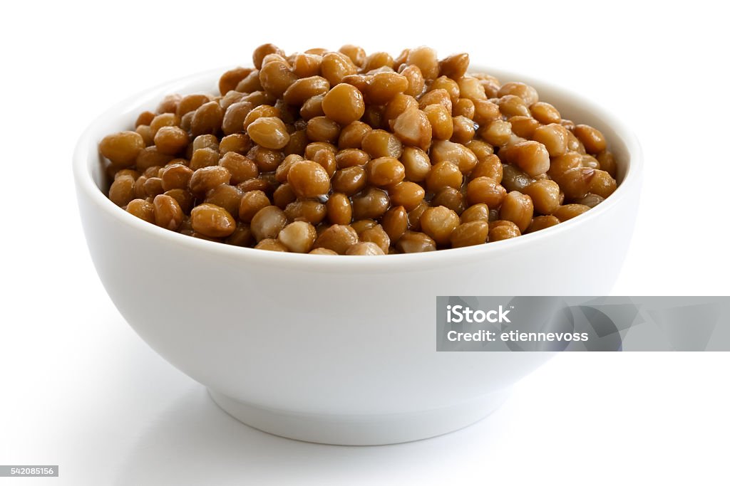 White ceramic bowl of brown cooked lentils isolated on white. White ceramic bowl of brown cooked lentils isolated on white in perspective. Lentil Stock Photo