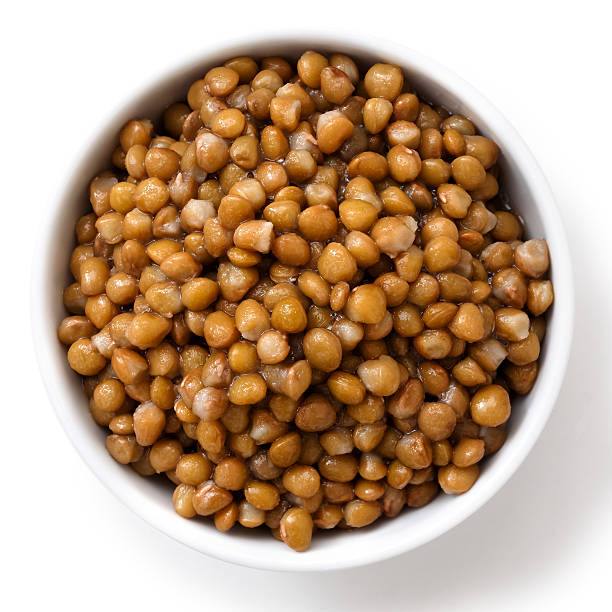 istock White ceramic bowl of brown cooked lentils isolated on white. 542085216