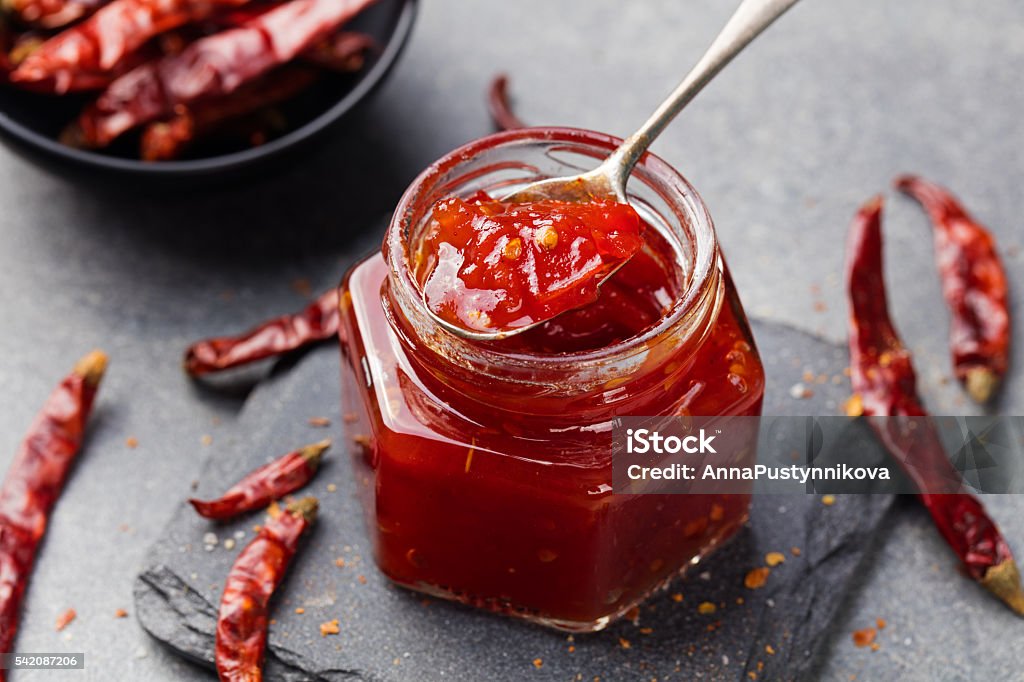 Tomato and chili sauce, jam, confiture in a glass jar Tomato and chili sauce, jam, confiture in a glass jar on a grey stone background. Preserves Stock Photo