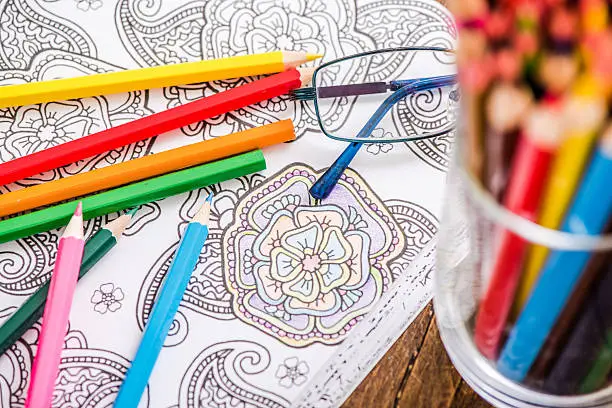 relaxing with adult coloring book, on wooden table