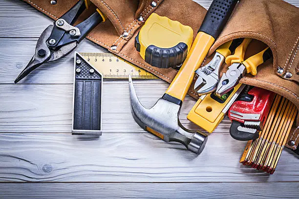 Leather tool belt with construction tooling on wooden board maintenance concept.