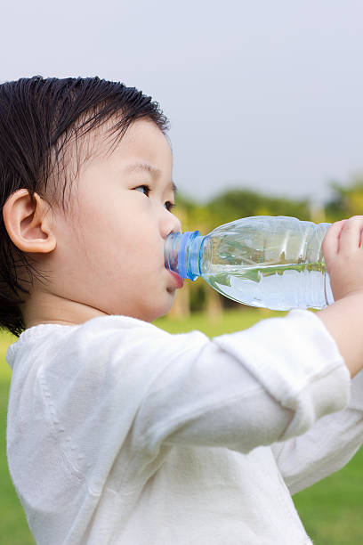 istock Little asian girl  drinking water from plastic bottle 542093708
