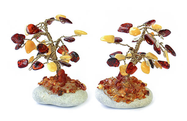 Tree statuette on the stone made of amber drops, isolated over white background