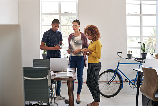 Shot of a group of colleagues having an informal meeting with a laptop in a modern office