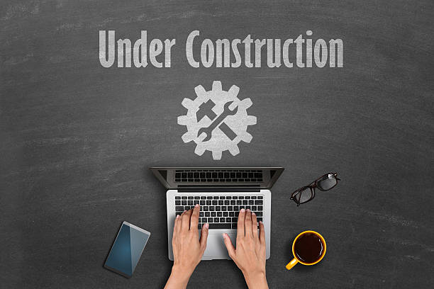 Under construction concept Top shot of person hands working on laptop and under construction text with it support icon drawn on blackboard. adjustable wrench photos stock pictures, royalty-free photos & images