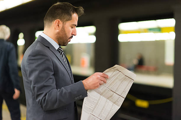 istock Commuter reading a newspaper while waiting for the subway train 542175596
