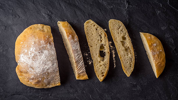 istock Sliced ciabatta on the dark stone table top view 542175626