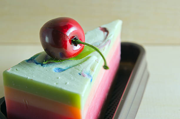 Fancy soap (cake piece) with cherry on the top on wooden board background