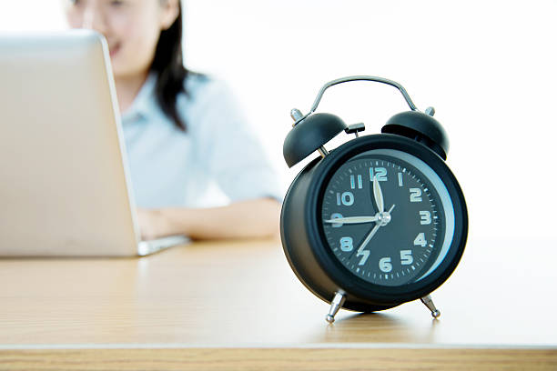 istock Businesswoman working on laptop with clock showing time 542181666