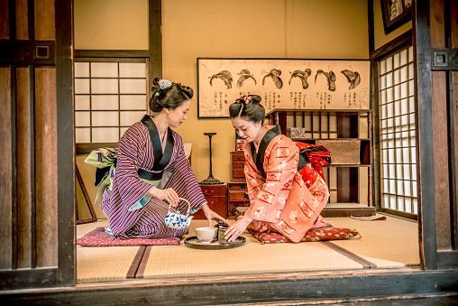 Beautiful smiling japanese women in kimono having matcha green tea at home, Edo period, indoors, Kyoto, Japan, Asia. They are talking, enjoying in traditional ceremony. Copy space. Nikon D800, full frame, XXXL. iStockaLypse Kyoto 2016.