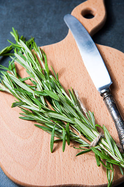 istock Bunch of fresh rosemary sprigs on a bamboo chopping board 542186036