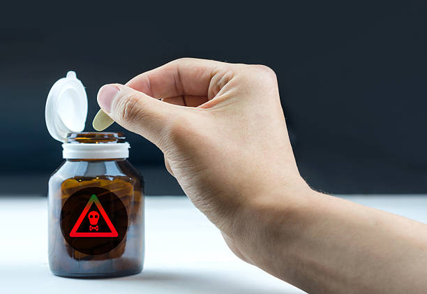 istock Toxic sign on tablets bottle with hand holding tablet 542188236