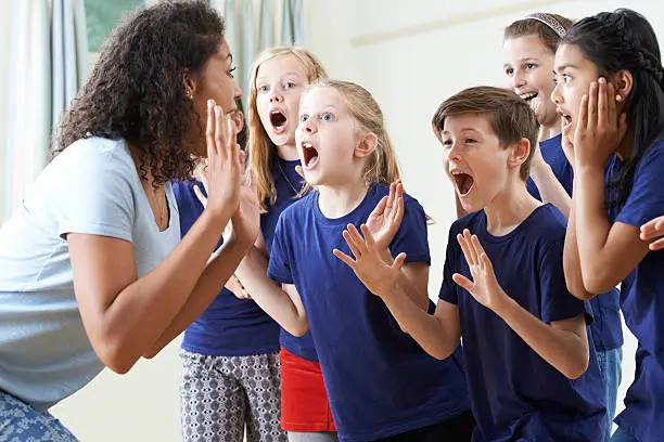 Photo of Group Of Children With Teacher Enjoying Drama Class Together