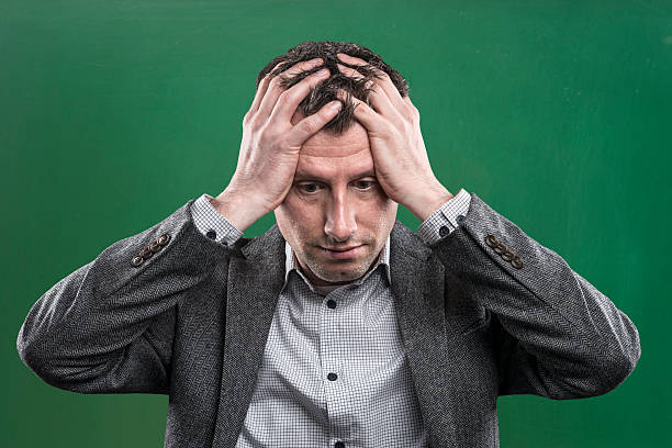 istock desperate teacher with grey hair at empty blackboard 542196460