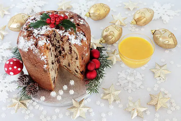Chocolate panettone christmas cake with holly and egg nog and gold and white bauble decorations.