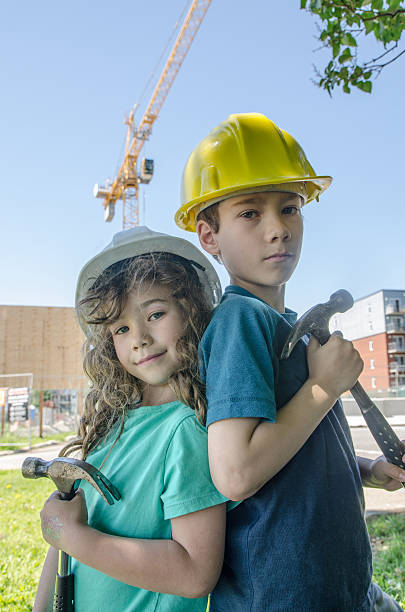 istock Two kids, wearing hardhat, in front of construction crane 542203266