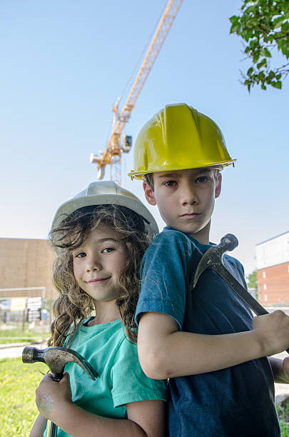 istock Two kids, wearing hardhat, in front of construction crane 542203294