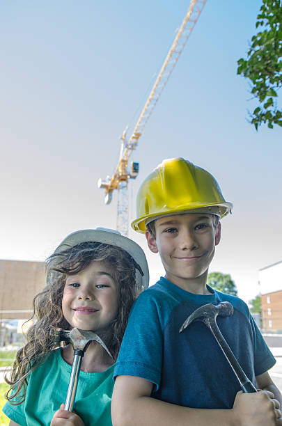 istock Two kids, wearing hardhat, in front of construction crane 542203358
