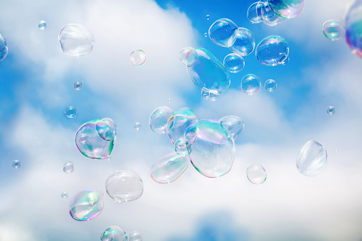 Soap bubbles floating in cloudy blue sky