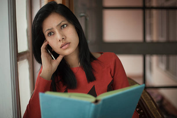 cubierta, sereno chica adolescente estudiante pensando cerca de la ventana con libros. - looking away asian ethnicity child little girls fotografías e imágenes de stock