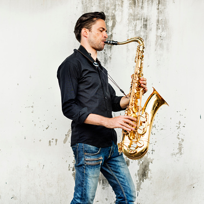 Teenage boy play saxophone at home