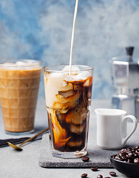 Ice coffee in a tall glass and coffee beans Ice coffee in a tall glass with cream poured over and coffee beans on a grey stone background. vietnamese culture photos stock pictures, royalty-free photos & images