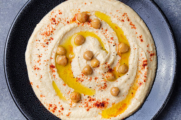 istock Hummus, chickpea dip, with spices Black plate on stone background 542213412