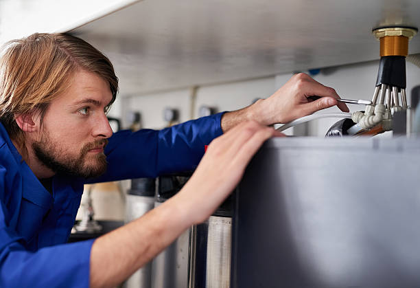 Getting to the root of the problem Shot of a handyman repairing a pipe on a water heater bathroom geyser stock pictures, royalty-free photos & images