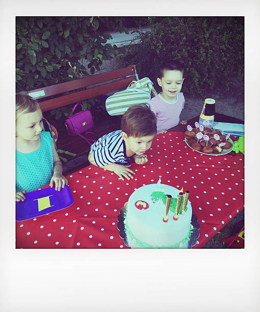 Blowing candles on a birthday cake Photo of a children at a birthday party blowing out candles on a birthday cake // polaroid // mobile stock photo  happy birthday cousin images stock pictures, royalty-free photos & images