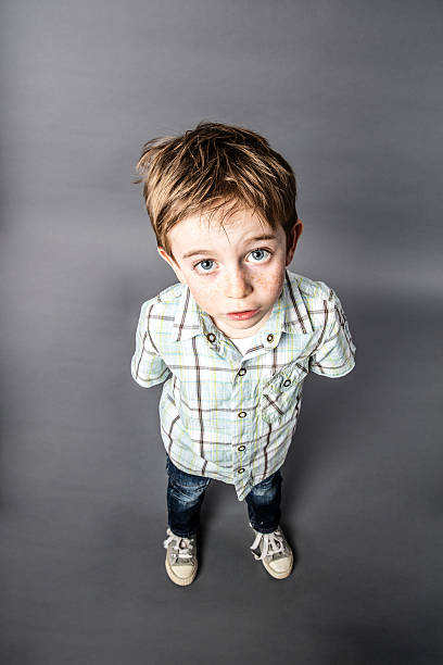 stunned beautiful young boy staring for surprise, high angle view stunned beautiful young 6-year old boy staring with wide-eyed standing for speechless surprise or misunderstanding, high angle view the boy standing eyes staring ahead stock pictures, royalty-free photos & images