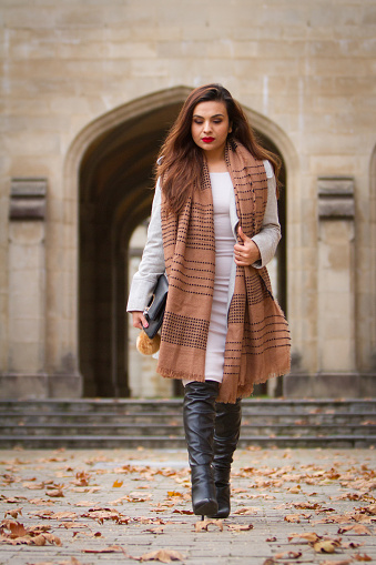 Full length shot of a well dressed young woman. Winter. Classic architecture surrounds.