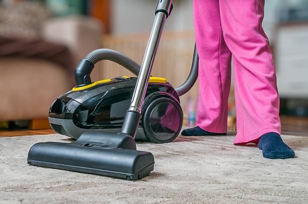istock Woman is vacuuming carpet with vacuum cleaner. 542284588