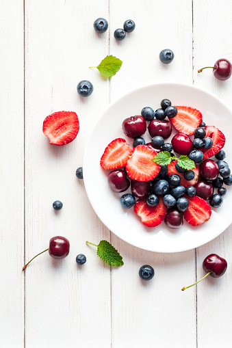 fruit salad on white wooden background, top view, flat lay