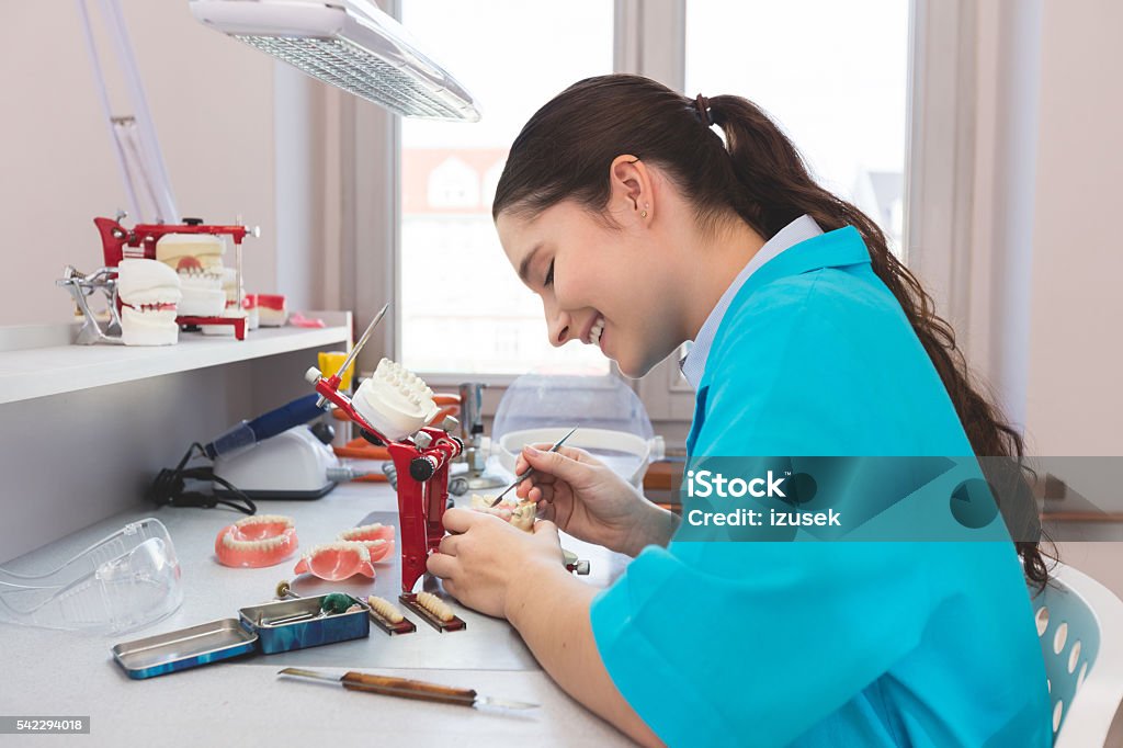 Female student learning prosthetic dentistry Young woman wearing uniforms in a prosthodontic lab, learning prosthetic dentistry. Technician Stock Photo
