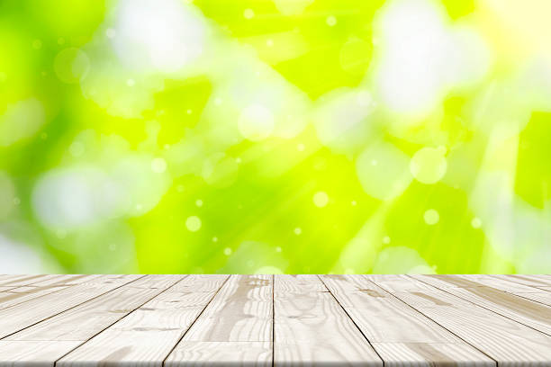 istock Wood table top on green blurred in background with sunlight 542296548