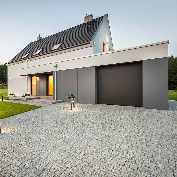 External view of stylish house with big garage and stone driveway