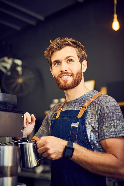 istock Smiling barista using steamer of coffee maker 542303016