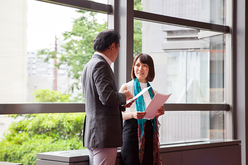 Two Japanese business colleagues go over the business documents together