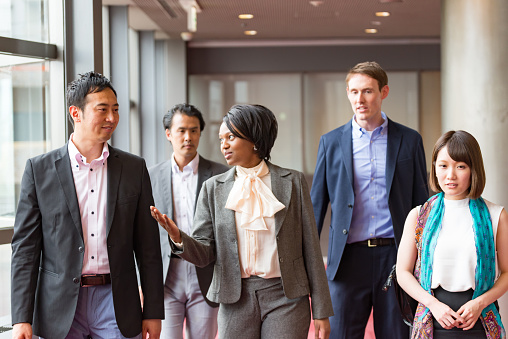 International businesspeople are walking together at hallway of office building