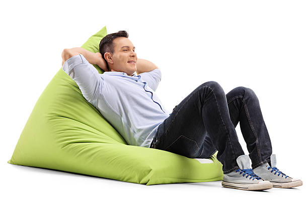 Relaxed guy laying on a beanbag Relaxed young guy laying on a comfortable green beanbag isolated on white background bean bag stock pictures, royalty-free photos & images