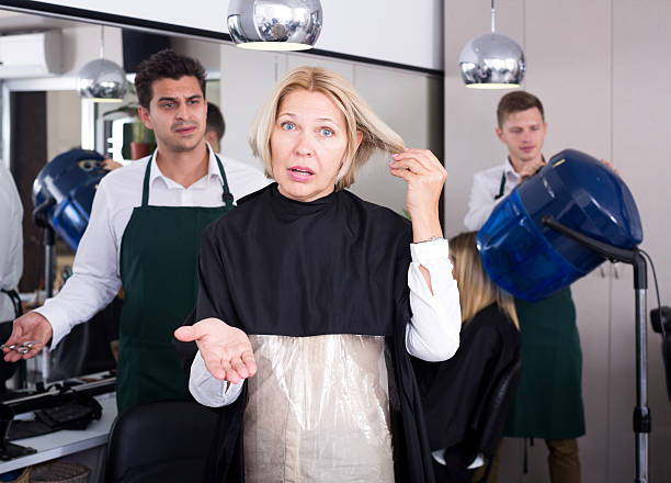 Frustrated female pensioner having fight with hairdresser Sad female pensioner having fight with hairdresser in salon. Focus on the woman angry hairstylist stock pictures, royalty-free photos & images