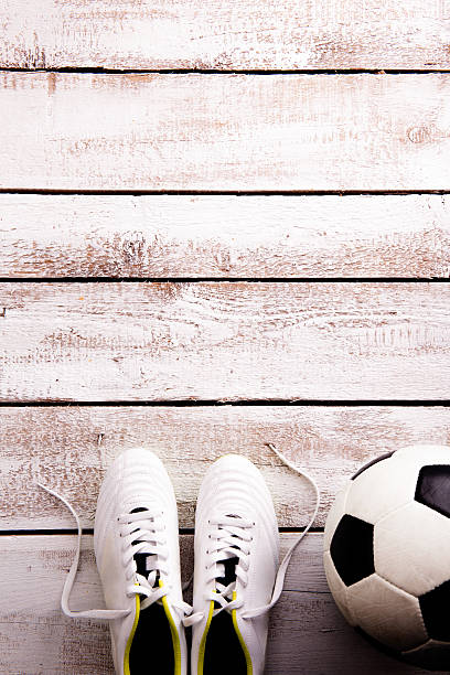 istock Soccer ball, cleats on white wooden floor, studio shot 542308472