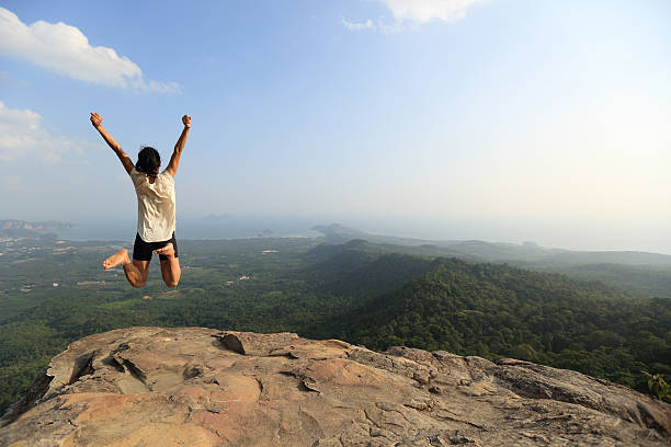 istock cheering young asian woman jumping on mountain peak rock 542309768