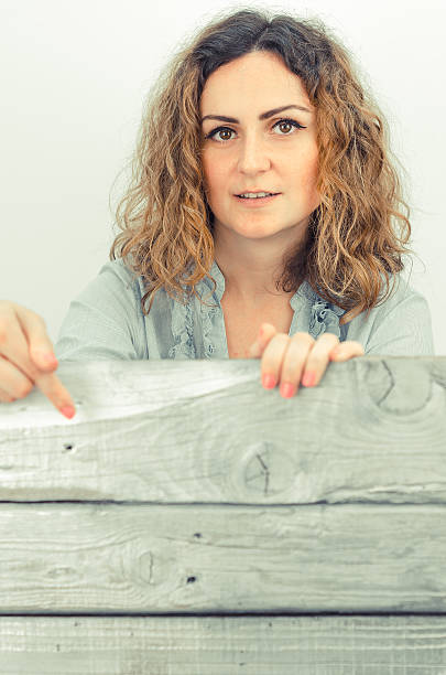 istock Young curly girl hides behind the silver planks or boards 542309840
