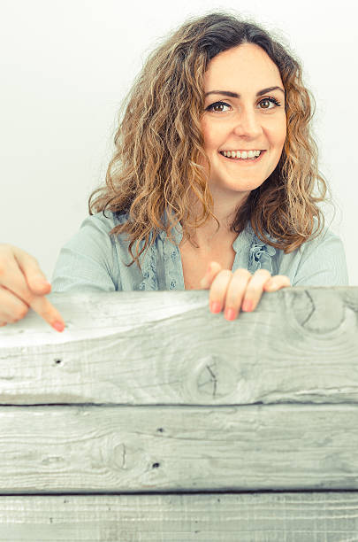 istock Young curly girl hides behind the silver planks or boards 542310018